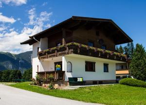 una casa en las montañas con flores en el balcón en Appartement Seidner Achleit 30, Angerberg en Angerberg