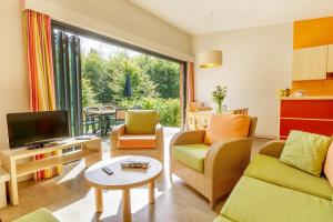 sala de estar con sofá y TV en Center Parcs Les Trois Forêts, en Hattigny