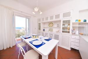 uma cozinha branca com uma mesa e uma janela em Casa Romano, centro di Forio, Ischia em Ischia