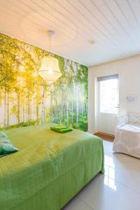 a bedroom with a green bed with a forest mural on the wall at Villa Sofia Barösund in Inkoo