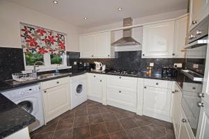 una cucina con armadi bianchi e una lavatrice/asciugatrice di Viewbank Cottage a Whiting Bay