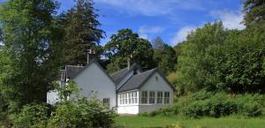 a white house in a field with trees at Achnacriche B&B in Bonnavoulin