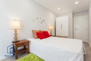 a bedroom with a large white bed with red pillows at Apartamento da estação in Setúbal