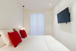 a white bed with red pillows and a flat screen tv at Fermin Suite - Iberorent Apartments in San Sebastián
