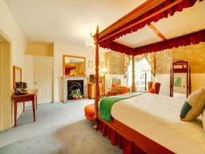 a bedroom with a canopy bed and a fireplace at OYO Bailbrook Lodge, Bath in Bath