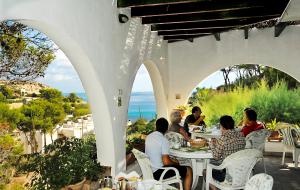a group of people sitting at a table on a patio at Hostal Los Pinos in Cala de Sant Vicenc