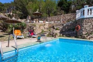 a swimming pool in front of a stone wall at Hostal Los Pinos in Cala de Sant Vicenc +8 photos