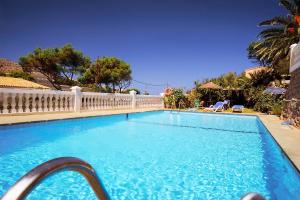 a large swimming pool with a white fence around it at Hostal Los Pinos in Cala de Sant Vicenc