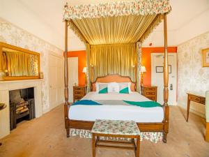 a bedroom with a canopy bed and a fireplace at OYO Bailbrook Lodge, Bath in Bath