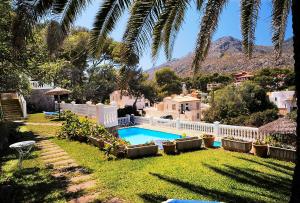 einen Hinterhof mit einem Pool und einem weißen Zaun in der Unterkunft Hostal Los Pinos in Cala de Sant Vicent