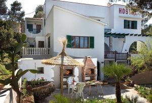a large white house with a table and a fireplace at Hostal Los Pinos in Cala de Sant Vicenc