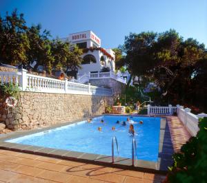 a group of people swimming in a swimming pool at Hostal Los Pinos in Cala de Sant Vicenc