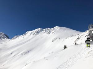 una montaña cubierta de nieve con un remonte en Résidence le Rami Les coches, en Les Coches