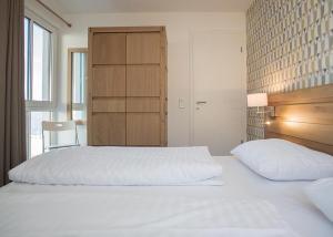 - une chambre avec 2 lits blancs et une armoire dans l'établissement Ferienwohnung Panoramablick Postwiese in Winterberg-Neuastenberg, à Winterberg