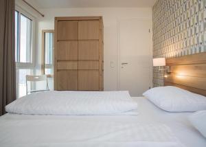 a bedroom with two white beds and a cabinet at Ferienwohnung Panoramablick Postwiese in Winterberg-Neuastenberg in Winterberg