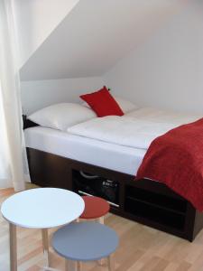 - un petit lit avec un oreiller rouge et 2 tables dans l'établissement Haus Meersburg See, à Meersburg