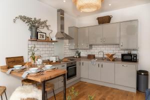 cocina con armarios blancos y mesa de madera en Finest Retreats - The Cotton Rooms en Matlock