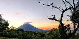 una montaña con una erupción volcánica en la puesta de sol en Finca del Sol Eco Lodge, en Santa Cruz