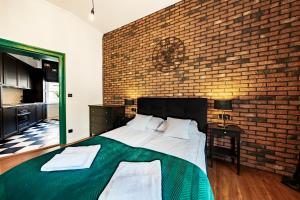 a bedroom with a large bed with a brick wall at Apartamenty Dominikańskie 2 in Toruń
