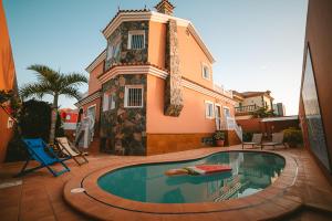 a house with a swimming pool in front of a house at Villa Morada Sonneland con piscina privada climatizada in Maspalomas