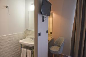 a bathroom with a sink and a tv on the wall at Auberge la Renaissance in Viarmes +38 photos