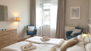 a bedroom with a bed and two chairs and a window at City Break Apartments - City Zen in Belgrade