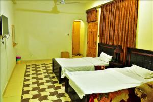um quarto de hotel com duas camas e uma televisão em River Palace Hotel em Suat