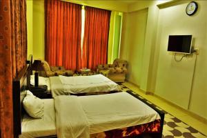 um quarto de hotel com duas camas e uma televisão em River Palace Hotel em Suat