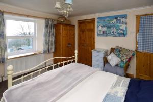 sypialnia z łóżkiem i krzesłem w obiekcie Vine Cottage w mieście Penpillick