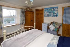 a bedroom with a bed and a chair in it at Vine Cottage in Penpillick