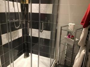 a shower with a glass door and black and white tiles at Garron View in Cushendall