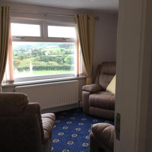 sala de estar con silla y ventana en Garron View, en Cushendall