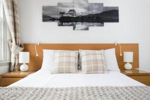 um quarto com uma cama branca e 2 candeeiros em Grassmarket Apartment em Edimburgo