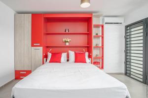 1 dormitorio con cabecero rojo y cama blanca en STUDIO EQUIPE A L ETANG Z ABRICOTS en Fort-de-France