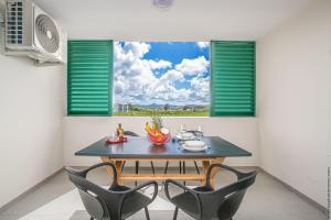 uma sala de jantar com uma mesa e cadeiras e uma janela em STUDIO EQUIPE A L ETANG Z ABRICOTS em Fort-de-France