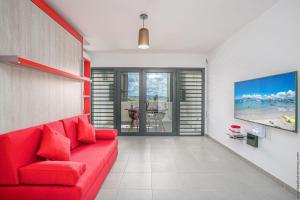 ein Wohnzimmer mit einem roten Sofa und einem Tisch in der Unterkunft STUDIO EQUIPE A L ETANG Z ABRICOTS in Fort-de-France