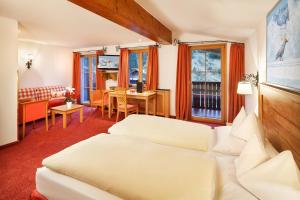 Habitación de hotel con cama y sala de estar. en Hotel Lech & Residenz Chesa Rosa, en Lech am Arlberg