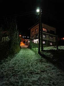 dom ze światłem na stronie pokrytej śniegiem ulicy w obiekcie Guesthouse Vazrozhdenski kashti w mieście Manastir
