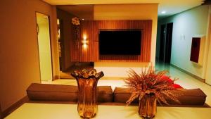 a living room with a couch and two vases on a table at Jardins Plaza Hotel in Sousa