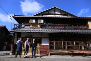 three people standing in front of a building at Guesthouse Izame Ann in Nagaoka