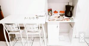 een witte tafel en twee witte stoelen in een keuken bij Cantinho Suico Aluguel de Temporada in Nova Friburgo