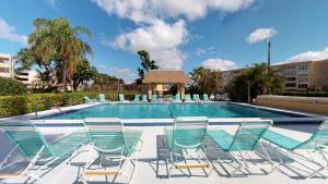 eine Gruppe von Stühlen vor einem Pool in der Unterkunft End Unit Steps from Beach Access w/ No Crazy Beach Prices in Marco Island