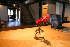 wazon kwiatów siedzący na stole z laptopem w obiekcie Guesthouse Izame Ann w mieście Nagaoka