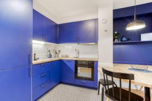 eine blaue Küche mit einem Tisch und blauen Schränken in der Unterkunft La Serrisienne 3 - Val d'Europe Place Toscane - Disneyland Paris - 4 à 6 Personnes in Serris + 16 Fotos