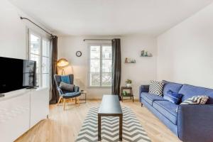 ein Wohnzimmer mit einem blauen Sofa und einem Fernseher in der Unterkunft La Serrisienne 3 - Val d'Europe Place Toscane - Disneyland Paris - 4 à 6 Personnes in Serris