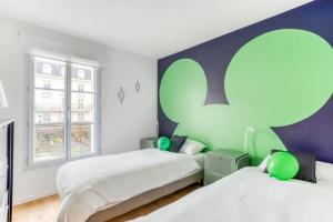1 Schlafzimmer mit 2 Betten und einer grünen und weißen Wand in der Unterkunft La Serrisienne 3 - Val d'Europe Place Toscane - Disneyland Paris - 4 à 6 Personnes in Serris