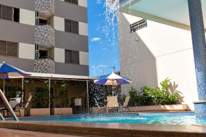 a swimming pool with a fountain in front of a building at Brumado Hotel in Campo Grande