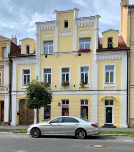 弗朗齊歇克礦泉村的住宿－Apartmány u Barči，停在黄色建筑前面的白色汽车