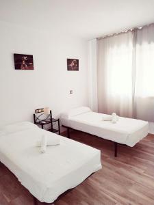 2 łóżka w pokoju z białymi ścianami i drewnianą podłogą w obiekcie Apartamento Ronda 4 - Los Boliches w mieście Fuengirola