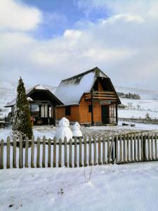 dos muñecos de nieve sentados en una valla delante de una casa en Brvnara Zlatiborka en Zlatibor